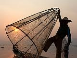 A fisherman raising his net at sunset