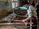 Picking up a page  The bath is a slurry of paper fibers.  The worker dips in a frame with a screen of bamboo fibers to form a new sheet of paper.