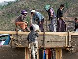 The making of a new farm house  Here, the walls are packed dirt, carried up by the man on the ladder and pounded into place by the women atop the wall.